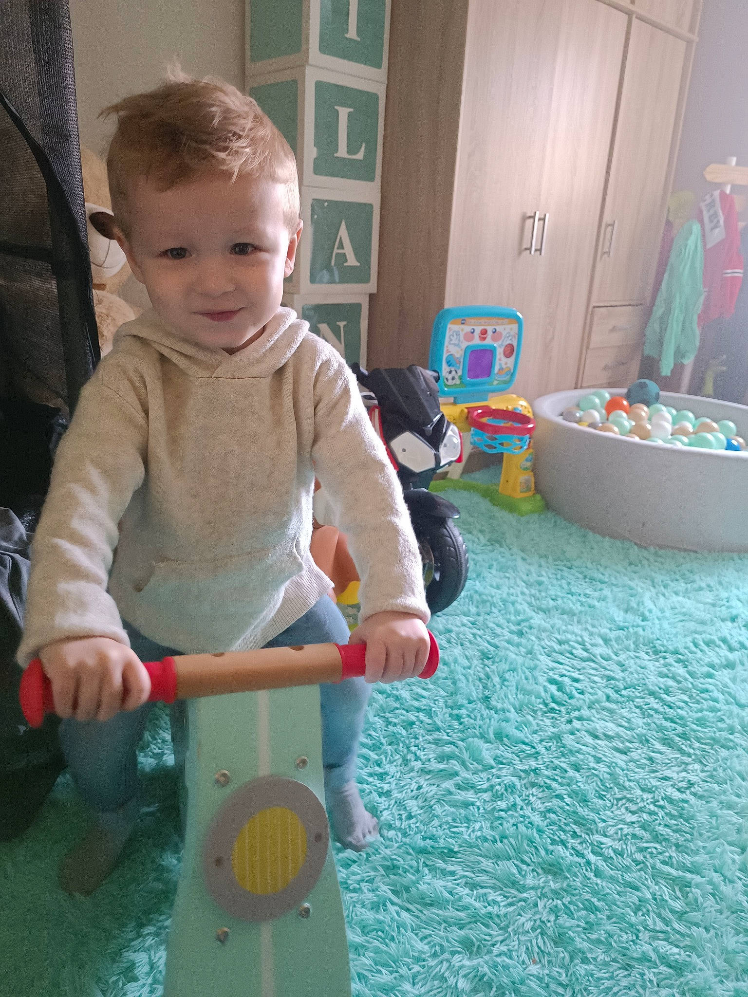 Ilann participe au concours pour gagner de l'argent avec cette photo : baby, baby_playing_with_toys, baby_products, baby_toddler_clothing, baby_toys, child, door, flooring, fun, happy, person, play, product, recreation, riding_toy, room, sitting, smile, standing, toddler