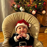 Hedy participe au concours pour gagner de l'argent avec cette photo : baby, child, christmas_tree, holiday, festive, santa_hat, striped_pants, smiling, chair, indoor, decorations, ornaments, lights, happy, cute, celebration, seasonal, christmas, toddler, cozy