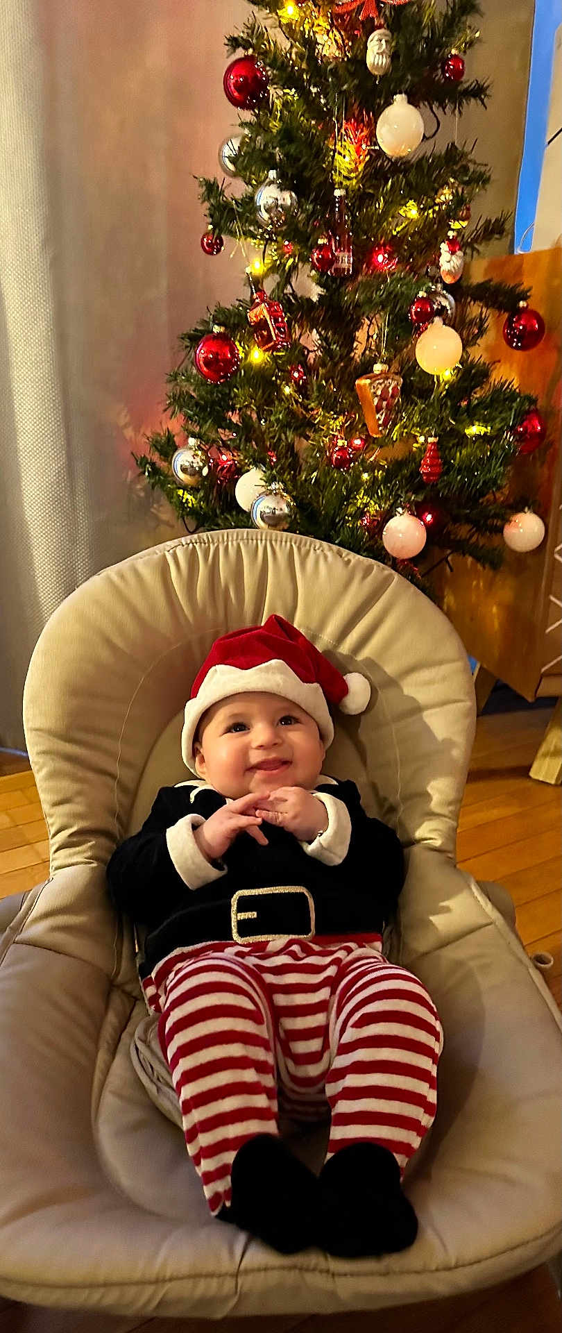 Hedy participe au concours pour gagner de l'argent avec cette photo : baby, child, christmas_tree, holiday, festive, santa_hat, striped_pants, smiling, chair, indoor, decorations, ornaments, lights, happy, cute, celebration, seasonal, christmas, toddler, cozy