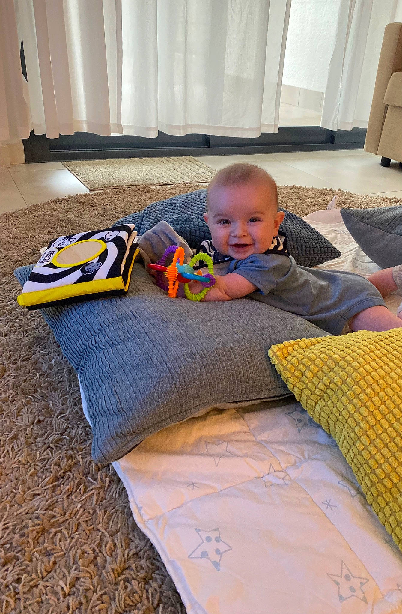 Blair is registered to the contest to win money with this photo: baby, bedding, carpet, child, comfort, crawling, floor, flooring, fun, grass, hardwood, linens, pattern, person, personal_protective_equipment, play, room, sitting, toddler, wood