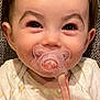 baby, pacifier, close_up, smiling, infant, cute, child, happy, face, hand, clothing, fabric_background, rainbow_print, sitting, indoors, young_child, holding, skin, portrait, expression