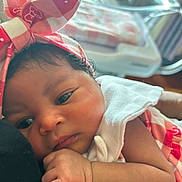 Ezsirae is registered to the contest to win money with this photo: baby, newborn, infant, headband, pink, checkered, clothing, closeup, face, hand, sleepy, resting, indoors, soft_light, portrait, person, cute, bassinet, fabric, skin