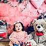 toddler, child, pink_dress, headband, snack_container, teddy_bear, plush_toy, carpet, heart_balloon, flowers, pink_background, bow_tie, sitting, indoors, cute, playful, portrait, young_child, decor, celebration