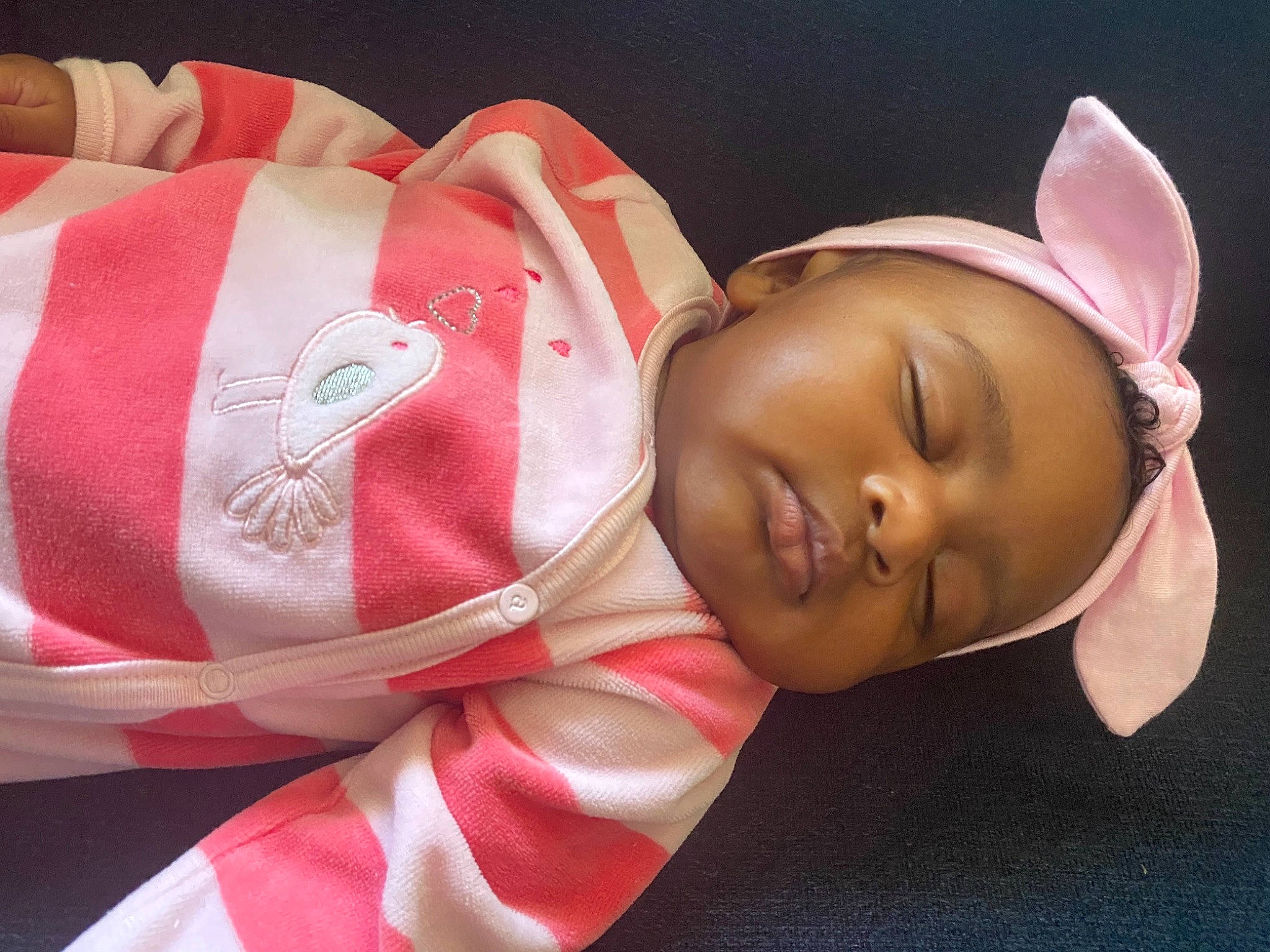 Leila is registered to the contest to win money with this photo: arm, baby, cheek, child, ear, face, forehead, hair_accessory, hand, head, headband, headgear, neck, nose, person, pink, skin, textile, toddler