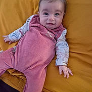 Eléna participe au concours pour gagner de l'argent avec cette photo : baby, infant, smile, face, clothing, blanket, yellow, pink, laying_down, cute, child, happy, person, indoors, soft, patterned_clothing, young, resting, cozy, portrait