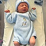 Rome is registered to the contest to win money with this photo: newborn, baby, sleeping, knitted_outfit, hat, blue_clothing, bunny_design, white_blanket, socks, infant, cute, cozy, peaceful, small_hands, lying_down, portrait, indoor, soft_light, baby_accessories, newborn_baby