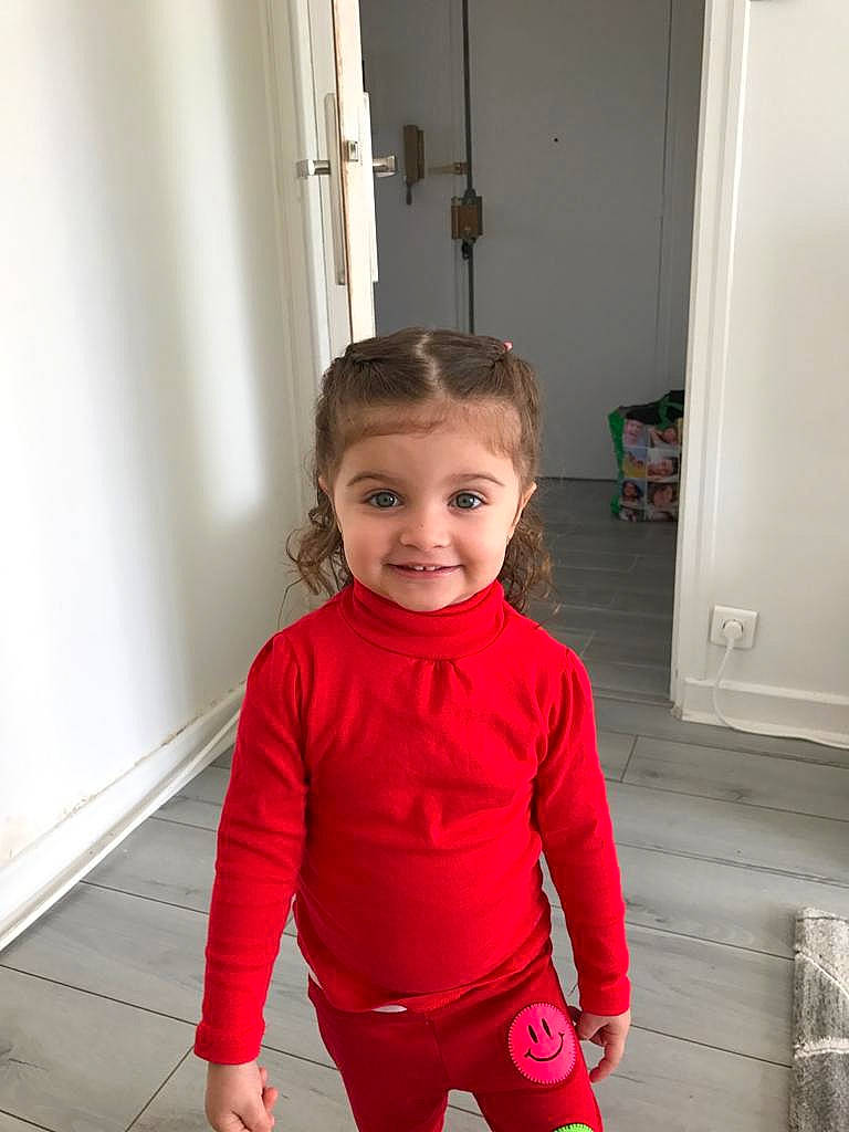 Sara a rejoint le concours — aidez-le/la à gagner de superbes lots ! baby_toddler_clothing, child, door, electric_blue, face, floor, flooring, happy, hardwood, head, joint, joy, person, sitting, sleeve, smile, sportswear, standing, t_shirt, toddler