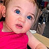 Echo is registered to the contest to win money with this photo: baby, child, blue_eyes, pink_bow, pink_clothing, table, hand, face, indoor, fan, person, curly_hair, expression, earrings, furniture, adult_partial, home, portrait, skin, cute