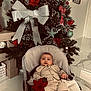 Tiago participe au concours pour gagner de l'argent avec cette photo : baby, child, christmas_tree, holiday, ornament, poinsettia, silver_bow, chair, indoor, floor, decor, festive, person, infant, clothing, marble_floor, plant, red_flower, holiday_decor, seasonal