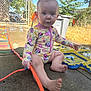 baby, barefoot, blue_eyes, child, concrete, curious, daytime, fence, garden, hair_tie, outdoor, person, plastic, play, sitting, summer, sunny, swimsuit, toy, water_toy