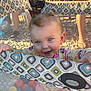 baby, blue_eyes, child, clothing, colorful, cute, face, feet, ground, hands, happy, mesh, outdoor, patterned_fabric, pigtails, playpen, shadow, smiling, sunlight, toys