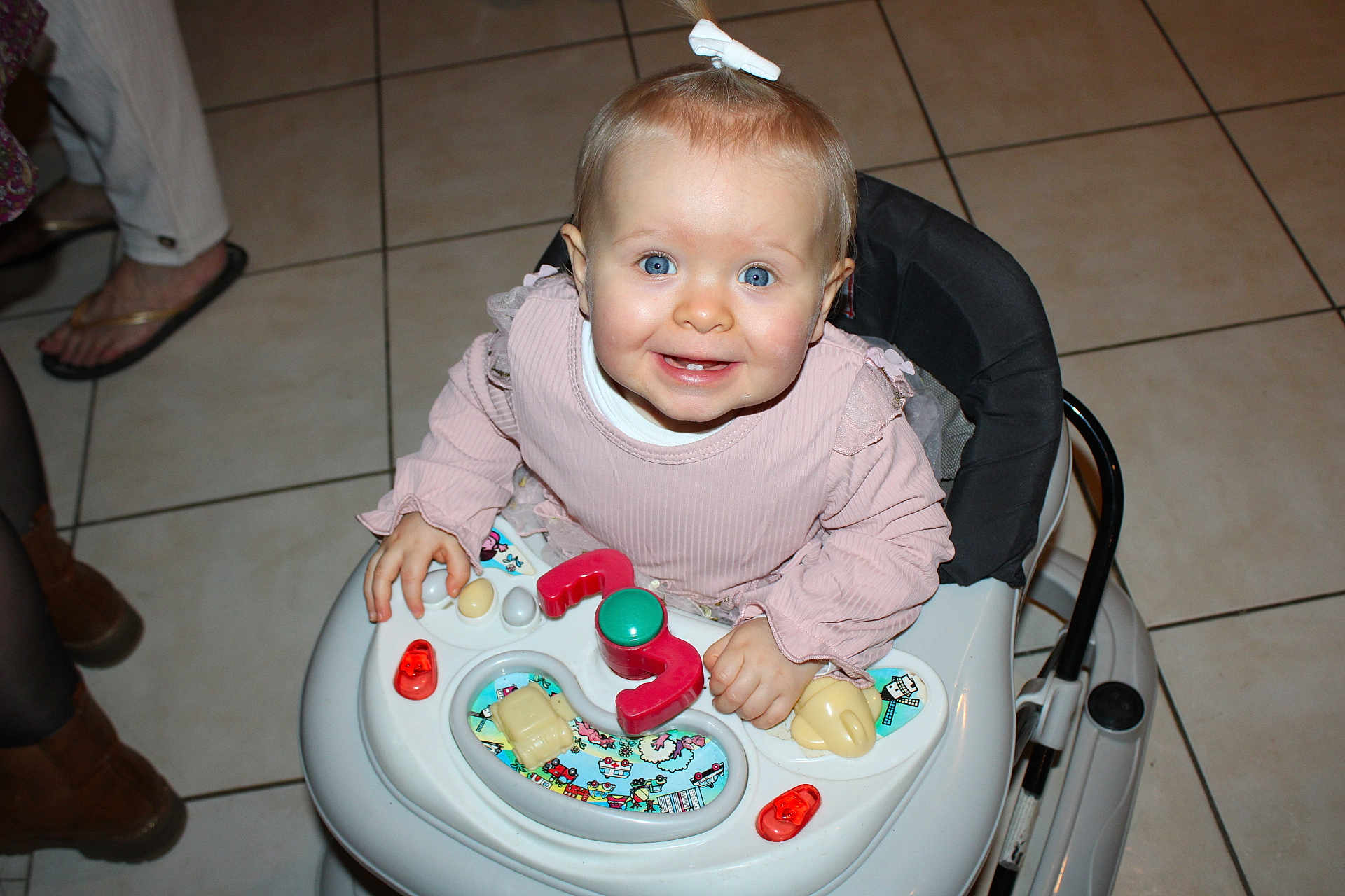 Steyla a rejoint le concours — aidez-le/la à gagner de superbes lots ! baby, blue_eyes, bow, candid, child, cute, family, floor_tiles, footwear, hands, happy, indoor, infant, person, pink_clothing, playing, smile, toy, walker, young_child