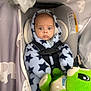 baby, infant, car_seat, harness, hooded_suit, star_pattern, plush_toy, green_toy, canopy, fabric, elephant_pattern, wide_eyes, surprised_expression, portrait, indoor, cozy, blanket, head_support, safety_label, gaze