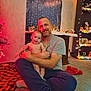 Isaiah is registered to the contest to win money with this photo: child, baby, adult, father, sitting, indoor, christmas, holiday_lights, decorations, tree, blanket, carpet, smile, portrait, cozy, cuddling, beard, tshirt, sweatpants, home_decor