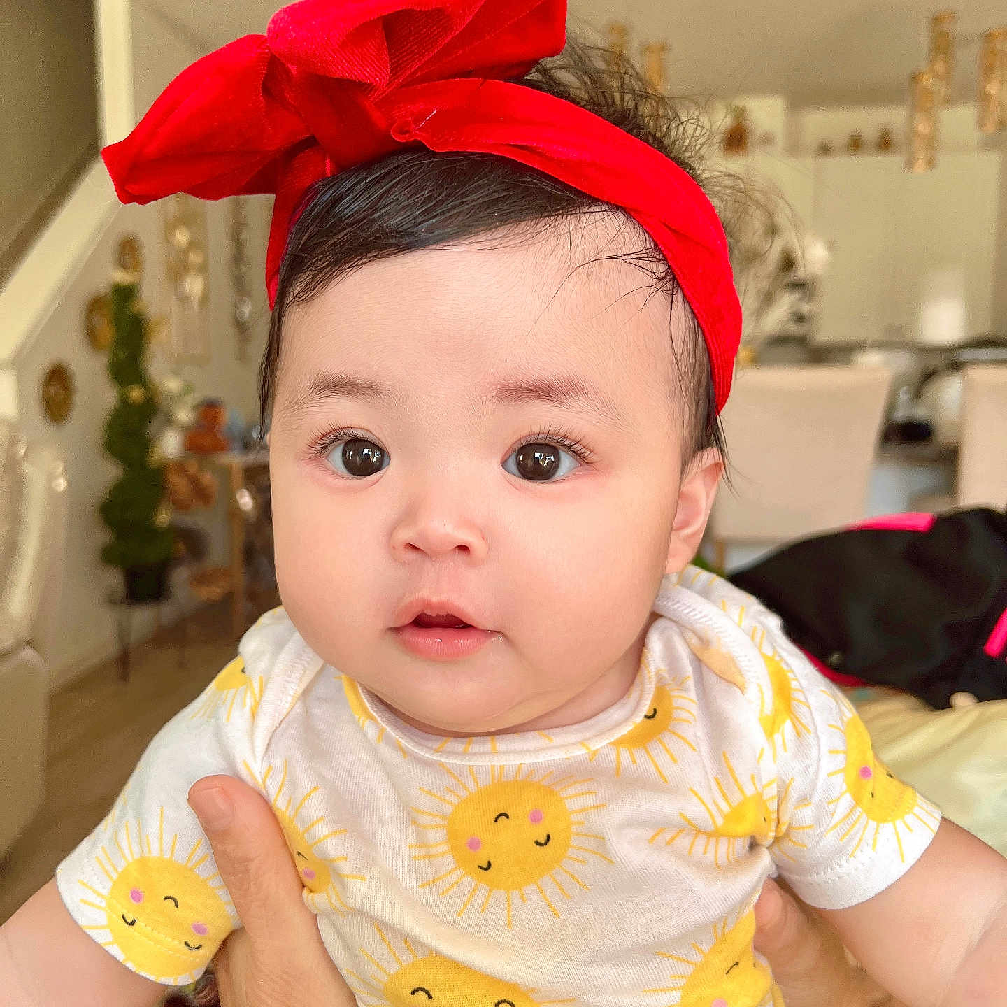 Autumn Brynnah is registered to the contest to win money with this photo: baby, child, curious_eyes, cute, face, furniture, hair, happy, holding_hands, home_interior, indoors, infant, onesie, person, portrait, red_headband, skin, smiling_sun, soft_lighting, sun_pattern