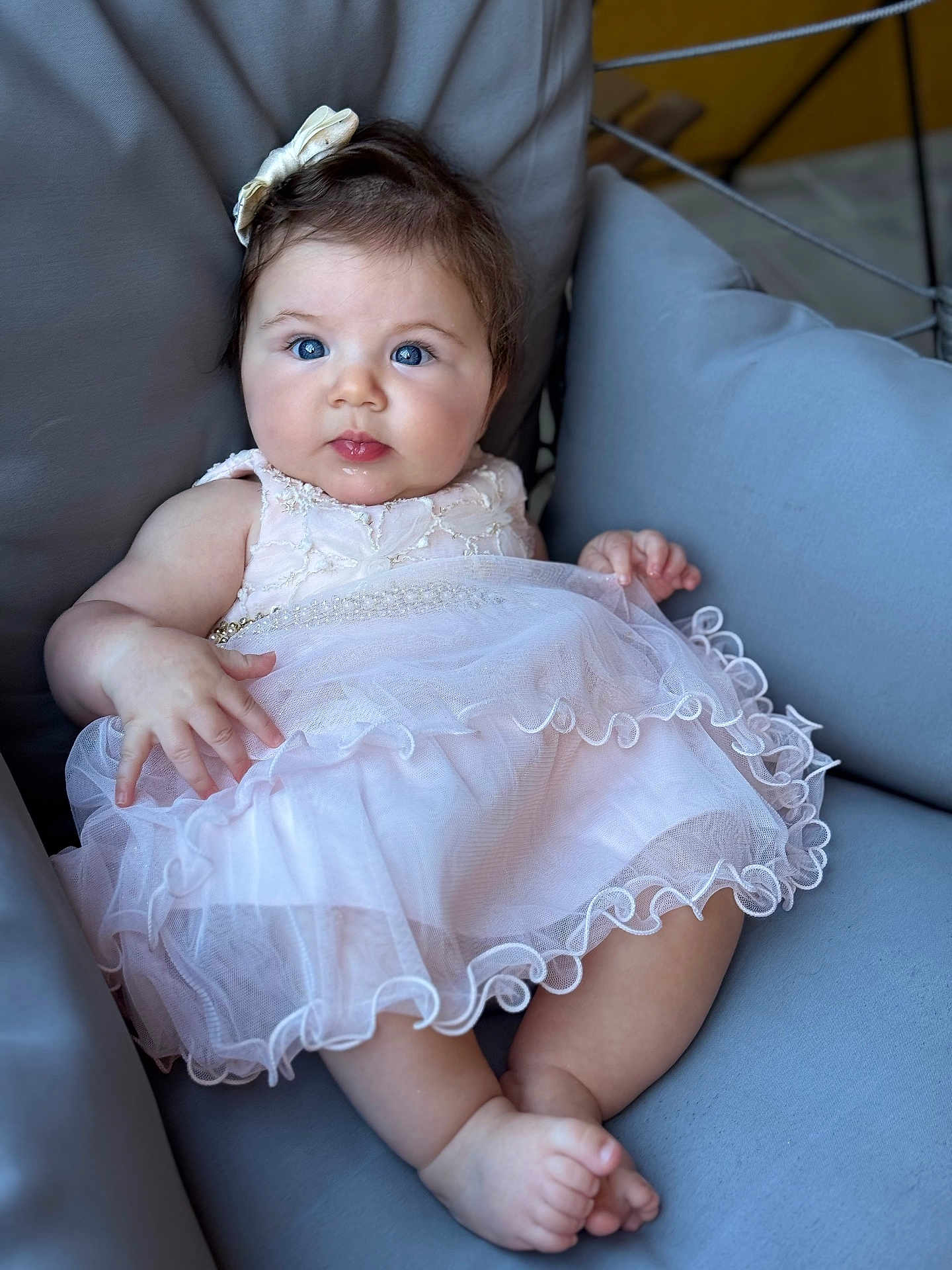 Sarah is registered to the contest to win money with this photo: baby, child, blue_eyes, dress, bow, sitting, couch, furniture, cute, portrait, infant, pink_dress, soft, indoors, adorable, young_child, smiling, skin, hand, foot