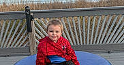 Tristan joined the competition — help win amazing prizes! child, toddler, boy, smiling, portrait, outdoor, waterfront, sea, ocean, reeds, boardwalk, deck, bench, cushion, blue, red, superhero, spiderman, casual_clothing, shoes