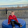 child, toddler, boy, smiling, portrait, outdoor, waterfront, sea, ocean, reeds, boardwalk, deck, bench, cushion, blue, red, superhero, spiderman, casual_clothing, shoes