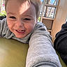 Tristan is registered to the contest to win money with this photo: child, toddler, smiling, happy, portrait, face, teeth, brown_hair, gray_shirt, long_sleeve, indoors, window, sunlight, table, candid, close_up, selfie, family, daylight, outdoor_view