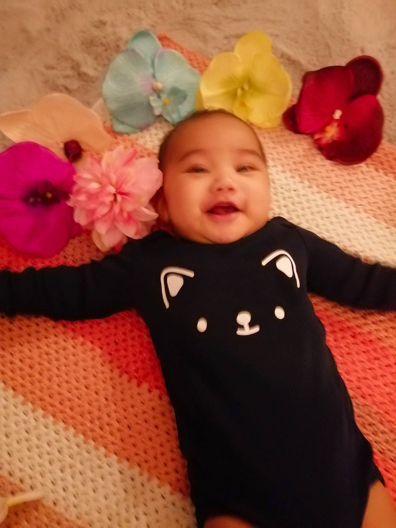 Rumatahina a rejoint le concours — aidez-le/la à gagner de superbes lots ! baby, baby_toddler_clothing, cheek, eye, face, facial_expression, happy, head, headgear, human_body, mammal, person, petal, pink, plant, red, skin, sleeve, smile, textile