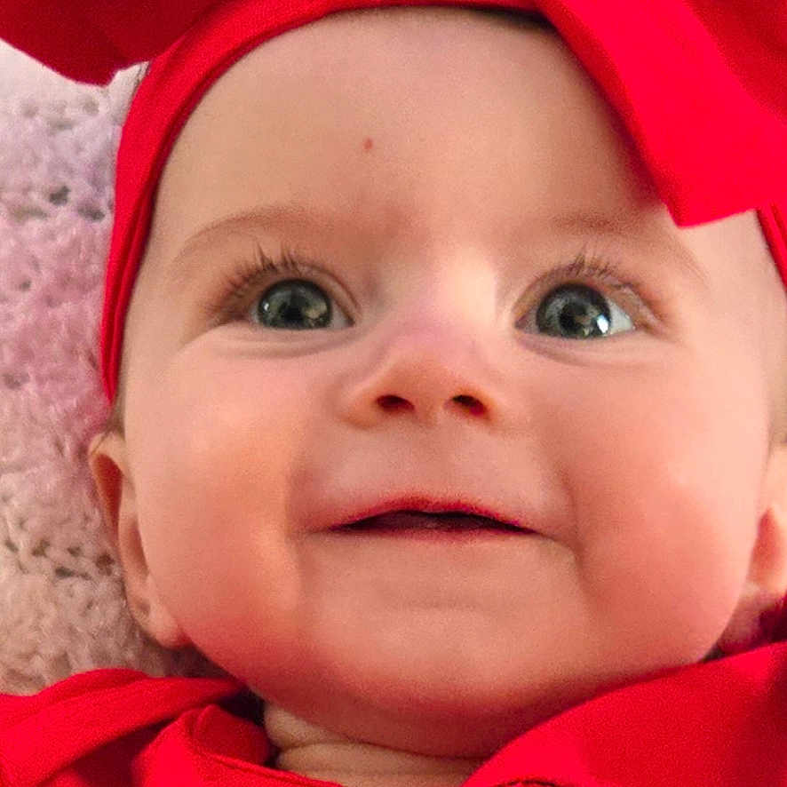 Lylajayne is registered to the contest to win money with this photo: baby, cheerful, child, closeup, colorful, cute, face, festive, hand, happy, holiday_theme, indoor, infant, portrait, red_clothing, red_headband, smiling, soft_texture, toy, young_child