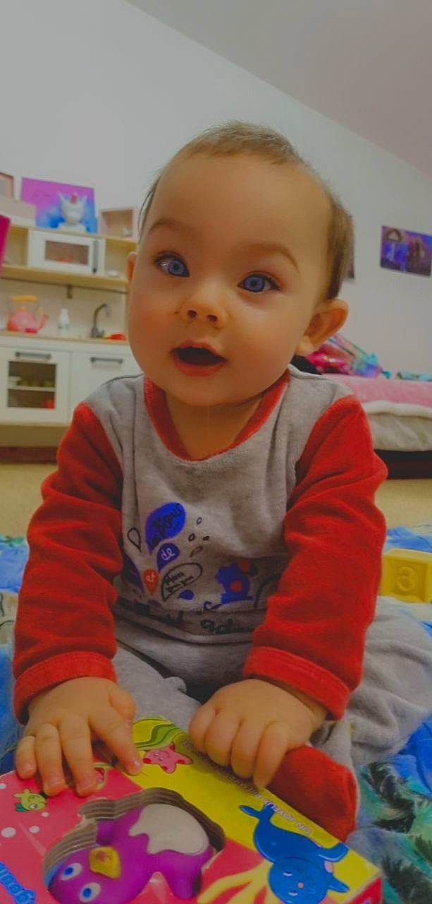 Eden a rejoint le concours — aidez-le/la à gagner de superbes lots ! baby, baby_playing_with_toys, baby_toddler_clothing, cheek, child, face, finger, flooring, fun, head, kindergarten, nose, person, play, room, sitting, skin, smile, standing, surprise