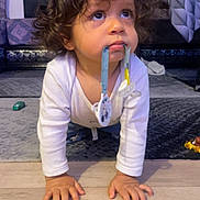 Mylhan a rejoint le concours — aidez-le/la à gagner de superbes lots ! toddler, child, baby, curly_hair, pacifier, crawling, floor, indoor, living_room, carpet, toy, white_clothing, hands, face, expression, looking_up, cute, young_child, home, curiosity