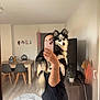 dog, pet, mirror_selfie, person, smartphone, reflection, living_room, dining_table, chairs, rug, television, plant, decor, hardwood_floor, tail, ears, blue_eyes, fur, holding, black_tshirt