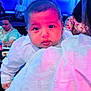 baby, child, infant, person, face, portrait, clothing, white_shirt, blanket, holding, indoor, people, adult, seated, table, food, drink, lighting, blue_light, pink_light