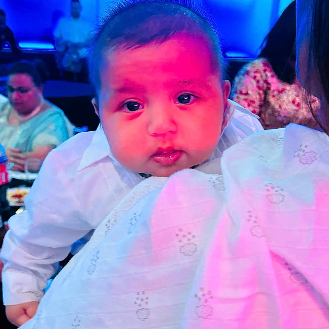 Taaj joined the competition — help win amazing prizes! adult, baby, blanket, blue_light, child, clothing, drink, face, food, holding, indoor, infant, lighting, people, person, pink_light, portrait, seated, table, white_shirt