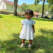 Calyana participe au concours pour gagner de l'argent avec cette photo : background_blur, blue_eyes, child, cute, daylight, grass, greenery, house, nature, outdoor, person, portrait, shoes, smiling, standing, sunny, toddler, trees, white_dress, young_child