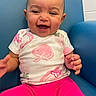 baby, child, smiling, happy, sitting, shirt, pink_pants, strawberry_print, blue_chair, indoor, person, cute, infant, portrait, young_child, toddler, clothing, furniture, joyful, face