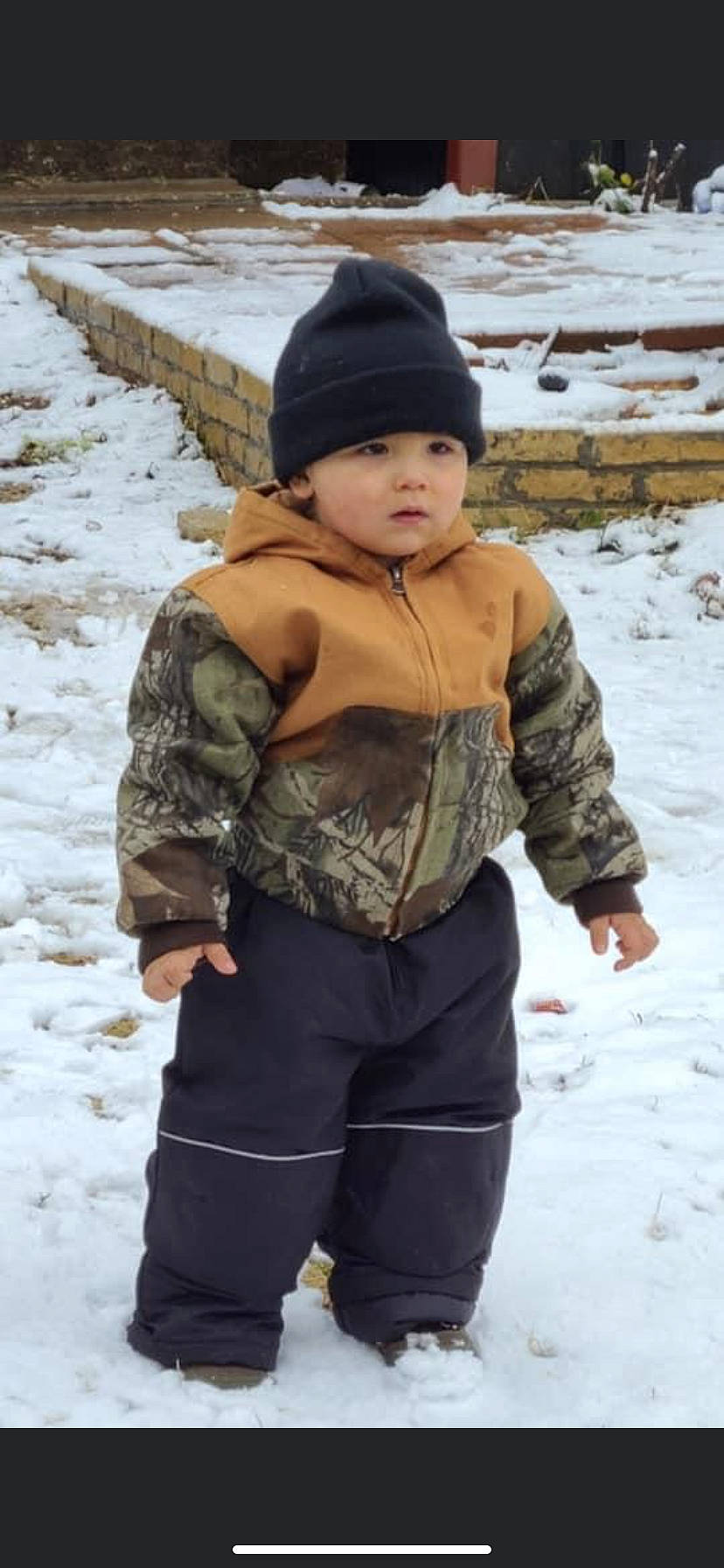 Xavier is registered to the contest to win money with this photo: active_pants, beanie, cap, cheek, child, face, freezing, fun, glove, head, headwear, knit_cap, military_camouflage, outerwear, pattern, person, playing_in_the_snow, recreation, sleeve, snow