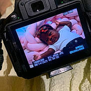 Princess joined the competition — help win amazing prizes! camera, screen, baby, infant, child, pink, cushion, braided, headband, white_shirt, portrait, indoor, soft_texture, close_up, digital_camera, photography, person, cute, resting, colorful