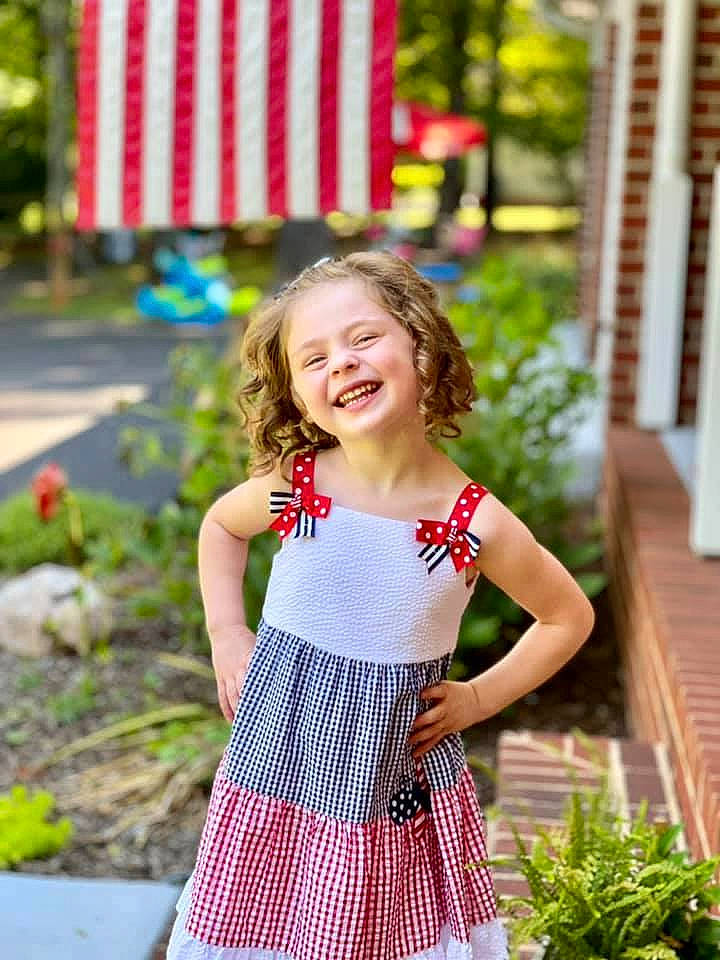 Raegan is registered to the contest to win money with this photo: day_dress, dress, eye, grass, green, happy, joy, leaf, leisure, people_in_nature, person, photograph, plaid, plant, red, sleeve, smile, street_fashion, summer, trunk