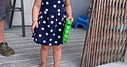 Kaleigh joined the competition — help win amazing prizes! child, toddler, girl, polka_dot_dress, barefoot, smiling, toy, porch, wooden_floor, outdoor, happy, person, short_hair, blue_dress, playful, daylight, home, fence, door, window