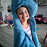 Kaleigh is registered to the contest to win money with this photo: child, smiling, blue_costume, hood, toy, living_room, floor, fan, playroom, furniture, happy, indoor, person, cute, plush, girl, clothing, smile, home, fun