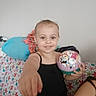Kaleigh is registered to the contest to win money with this photo: child, smiling, ball, pointing, couch, floral_pattern, cushion, clothing, indoor, person, happy, toy, face, sitting, casual, young, home, colorful, gesture, portrait
