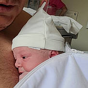 Dhevann a rejoint le concours — aidez-le/la à gagner de superbes lots ! adult, baby, newborn, hospital, nurse, hat, glasses, white_clothing, blanket, close_up, indoor, person, skin, face, holding, portrait, headwear, healthcare, care, tenderness