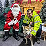 beard, boots, christmas, christmas_trees, decorations, dog, festive, fireplace, glasses, green_couch, holiday, husky, indoor, leash, man, santa_claus, smiling, stockings, winter, yellow_jacket