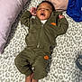 baby, infant, child, person, bed, blanket, pillow, clothing, tracksuit, nike, foot, face, hair, pattern, fabric, relaxed, indoors, laying_down, cute, sleepwear