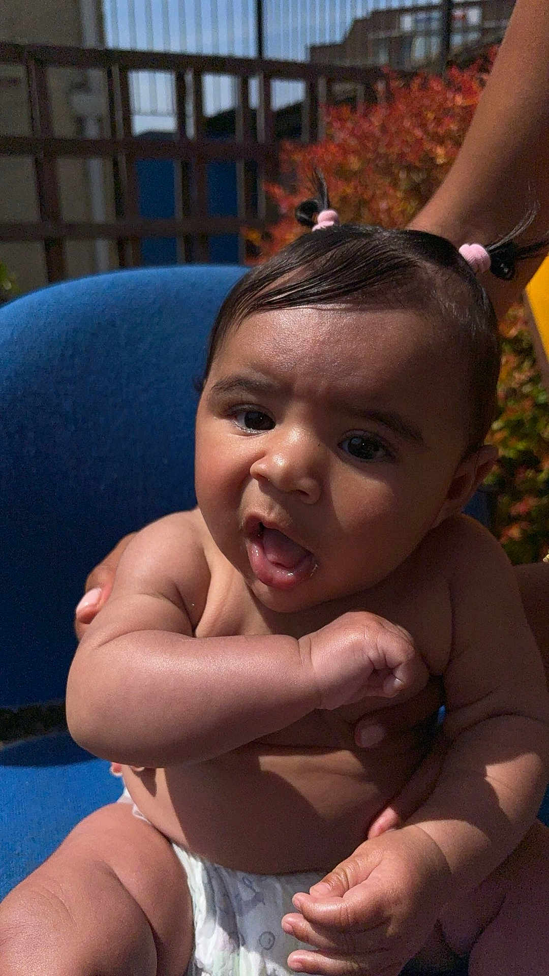 Zavannah joined the competition — help win amazing prizes! baby, infant, child, pigtails, diaper, arm, hand, face, expression, outdoor, blue_chair, sunlight, skin, person, cute, curious, plump, summer, nature, holding