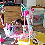 Zavannah is registered to the contest to win money with this photo: baby, activity_jumper, pink, smiling, indoor, television, dresser, fridge, toy, carpet, floor_mat, clothing, person, child, furniture, living_room, happy, play, mickey_mouse, household