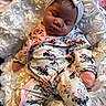 baby, sleeping, infant, headband, bow, floral_print, onesie, blanket, soft_texture, pink, white, cute, peaceful, newborn, portrait, closeup, indoors, child, resting, cozy