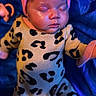 baby, sleeping, infant, pink_bow, headband, leopard_print, onesie, blue_blanket, soft_skin, peaceful, cute, child, portrait, indoors, warm_lighting, cozy, newborn, apparel, resting, adorable