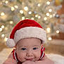 baby, infant, santa_hat, christmas, holiday, smiling, face, cute, soft, blurred_background, lights, festive, red, white, skin, portrait, holiday_decor, indoor, child, happy