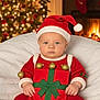 baby, infant, christmas, holiday, santa_hat, gift_wrap, red_clothing, green_ribbon, gold_ornaments, fireplace, christmas_tree, stockings, blanket, cozy, festive, indoors, cute, child, holiday_decoration, portrait