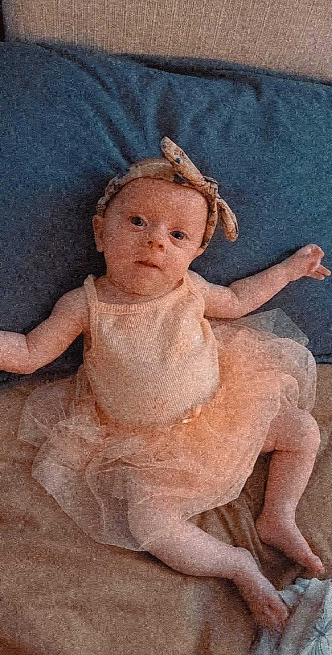 Odette is registered to the contest to win money with this photo: baby, baby_toddler_clothing, bridal_accessory, cheek, dress, embellishment, eye, eyebrow, eyelash, fashion_accessory, headband, headpiece, iris, jewellery, pattern, peach, person, pink, ruffle, sleeve