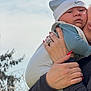 baby, infant, newborn, adult, hand, nails, rings, beanie, hat, outdoors, sky, clouds, trees, holding, hug, portrait, clothing, cheeks, expression, parent