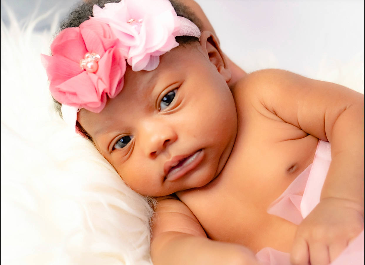 Aubrielle is registered to the contest to win money with this photo: arm, baby, baby_toddler_clothing, cheek, comfort, dress, eye, eyebrow, eyelash, face, facial_expression, gesture, happy, head, headwear, lip, nose, person, pink, skin